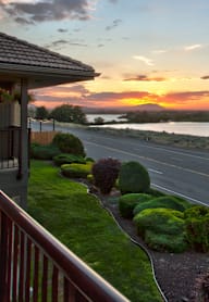 A sunset view from a house with a road and greenery in the foreground.