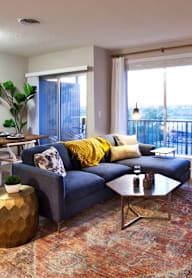 A blue couch with a yellow pillow is in the middle of a living room.