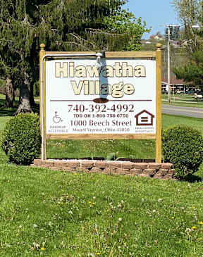 A sign for Hiawatha Village with a phone number and address.
