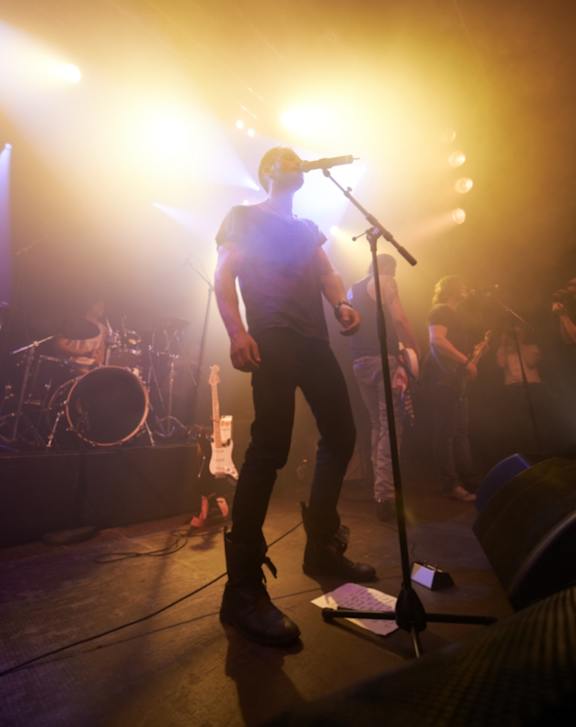 A musician is performing on stage with a microphone in hand.