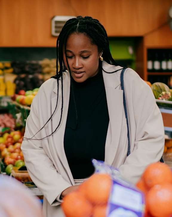 A woman is shopping for oranges in a grocery store.