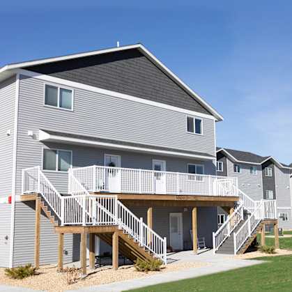 A grey and white apartment building with a balcony and stairs.