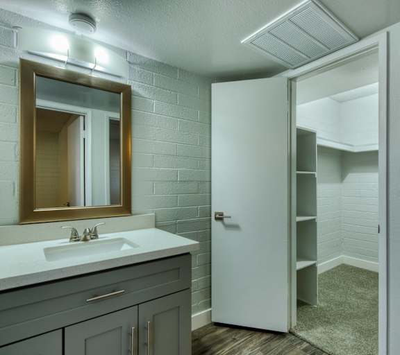 A bathroom with a sink, mirror, and a white door. at The Link Apartments, Arizona, 85201