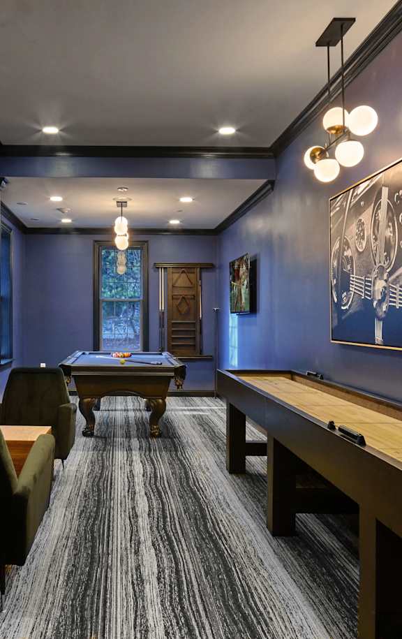 A room with a long table and chairs, a chess board, and a painting on the wall.