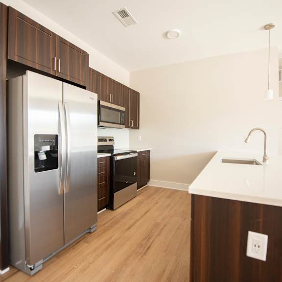 A modern kitchen with a stainless steel refrigerator and wooden cabinets.
