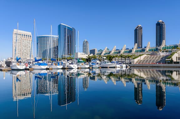 A cityscape with tall buildings and boats docked in the water.