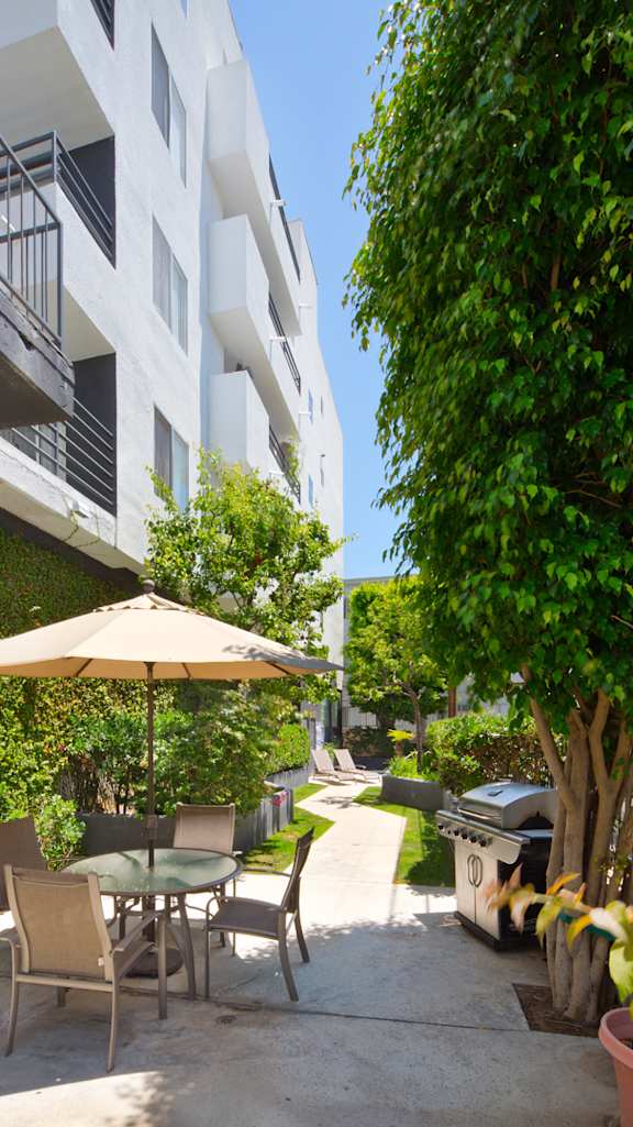 A patio with a table and chairs and an umbrella at Midvale Towers Apartments Westwood, California 90024