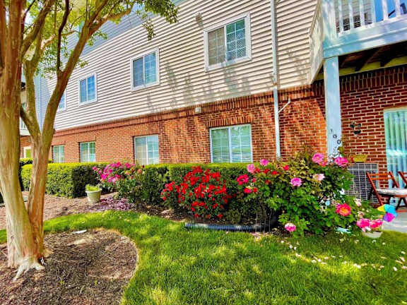 the front yard of an apartment building with flowers and grass at Greenbrier Seniors Apartments, Chesapeake