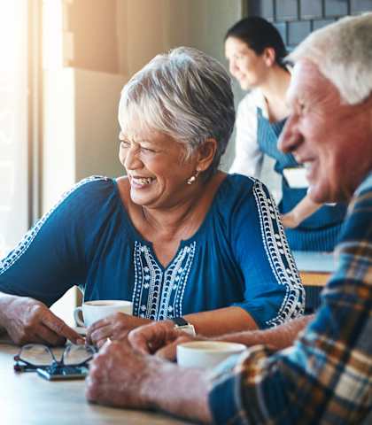 elderly people are sitting around a table, laughing and enjoying each other's company.
