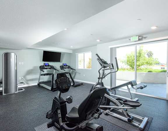 a gym with exercise machines and a tv on the wall