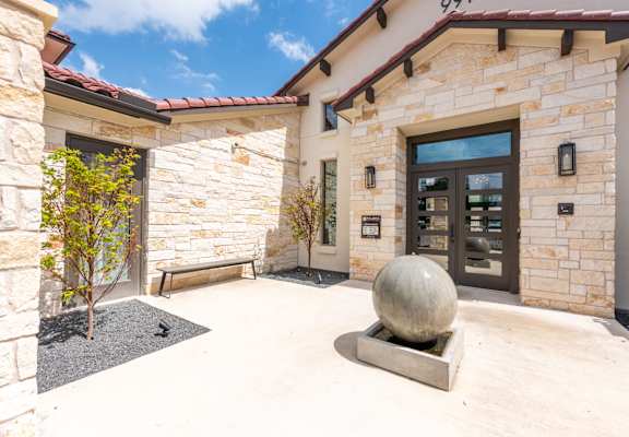 the front yard of a building with a ball and a bench