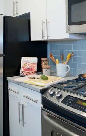 A modern kitchen with a black fridge, stove, and microwave at The Ellington Apartments, New York, NY, 10019