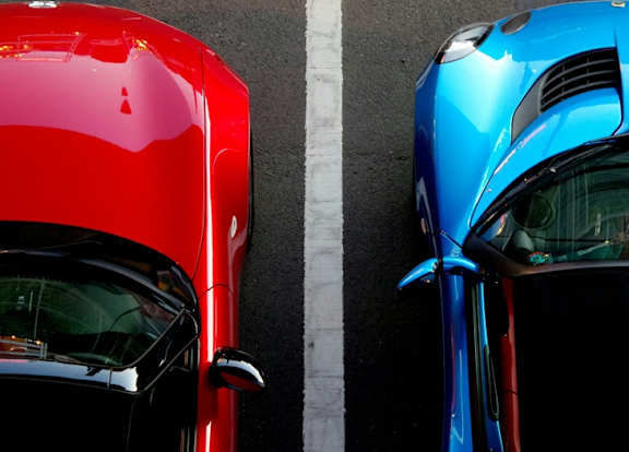 Two cars parked next to each other, one red and one blue.
