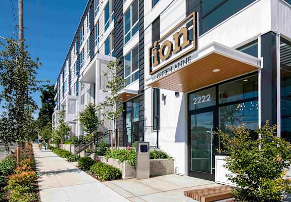 A Hilton hotel is located on a sidewalk with a landscaped area in front.