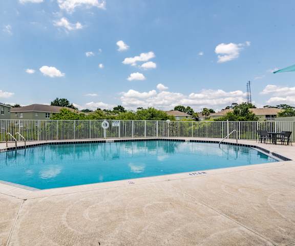A swimming pool surrounded by a concrete patio and a metal fence.