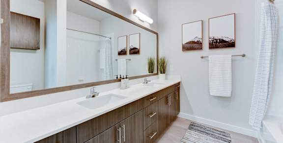 A bathroom with a white countertop and brown cabinets.