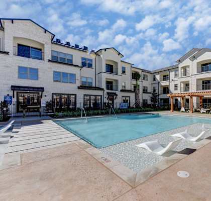 A large swimming pool in front of a building with a fence around it at Bridge at Speyside Apartments, Texas, 78754