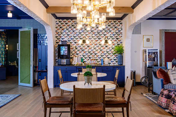 A dining room with a table set for two and a chandelier hanging from the ceiling.