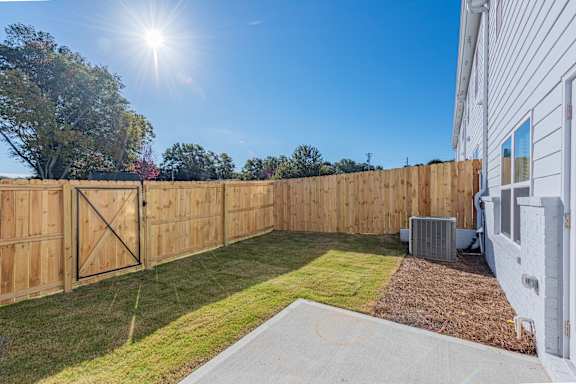 the backyard of a house with a wooden fence and a yard with grass
