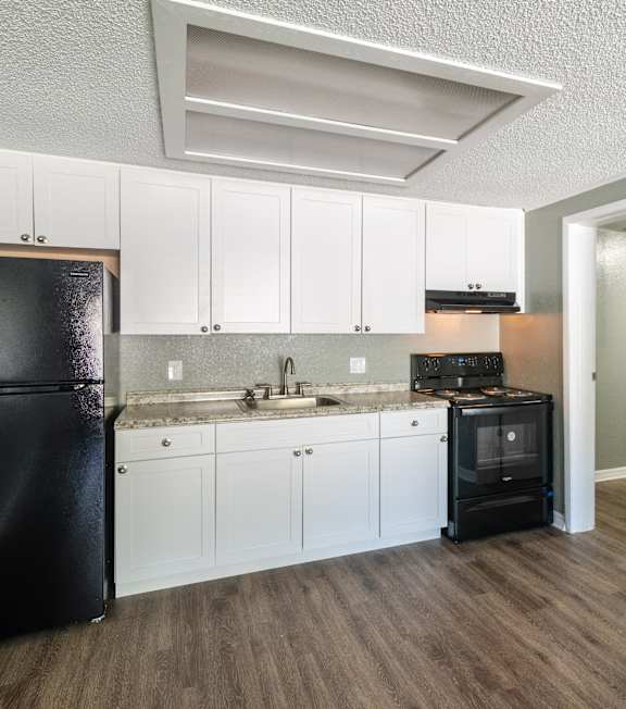 A black fridge and white cabinets in a kitchen.