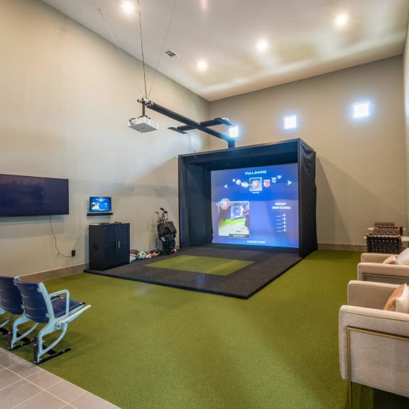 a game room with a projector screen and chairs on a green carpet