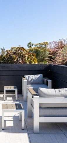 A patio with white furniture and a black wall.