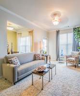 A living room with a grey couch, a coffee table, a chair, and a TV mounted on the wall.