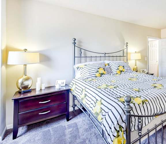 A bedroom with a bed, nightstand, and lamp. at Ashton Heights Apartments, Suitland, MD