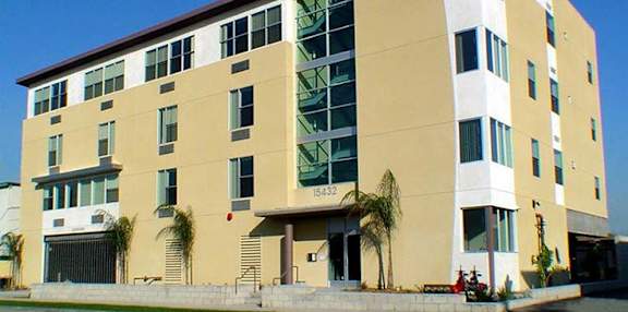 A modern building with a yellow and white facade and a clear blue sky in the background.