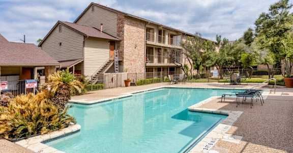 A swimming pool in a residential area with a building in the background.