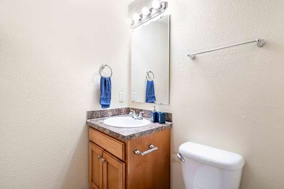 A bathroom with a toilet, sink, and mirror.