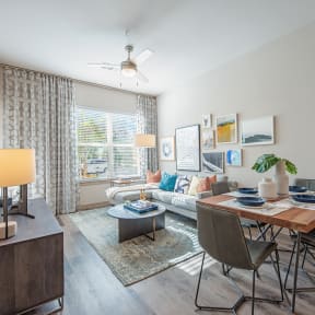 a dining area with a wooden table and chairs and a living room with a window
