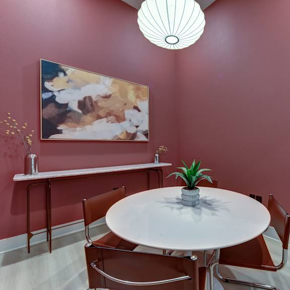 A white table with a pineapple on top is in the middle of a room with a pink wall. at Bridge at Saffron, Austin, TX