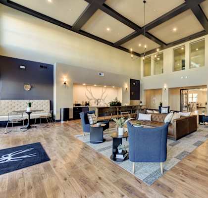 A spacious living room with a dark wood floor and a mix of blue and white furniture.