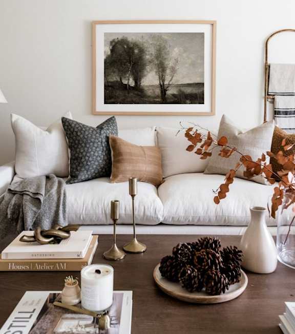 A living room with a white couch, a coffee table, and a framed picture on the wall.