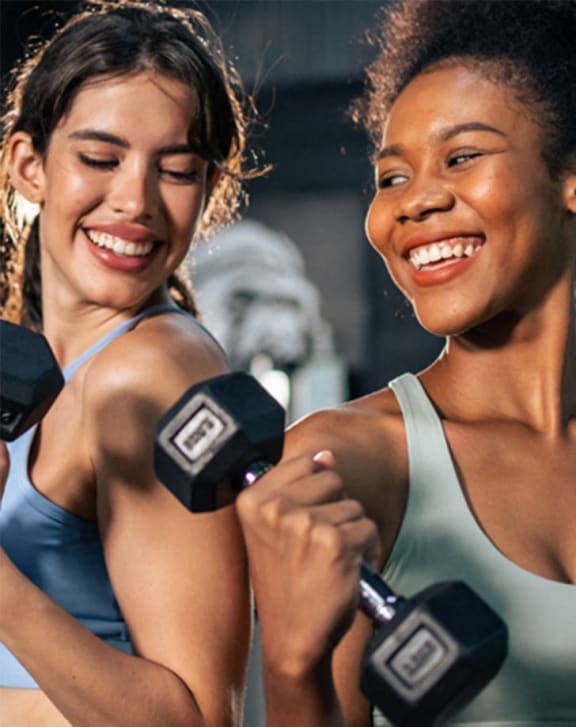two women lifting dumbbells at the gym