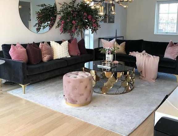 a living room with black furniture and pink pillows