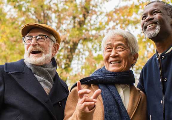 Three elderly people are standing together and smiling.