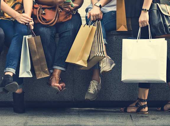 people sitting on a bench holding shopping bags