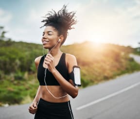 a woman running down a road with earphones in her ears