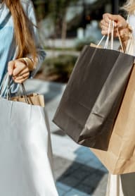 two women holding shopping bags and walking down the street