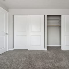 an empty bedroom with two doors and a closet