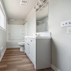a bathroom with a toilet sink mirror and shower in a 555 waverly unit