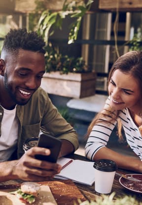a man and woman sitting at a table looking at a cell phone
