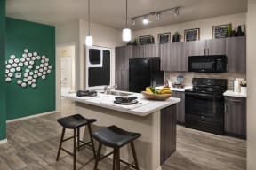a kitchen with black appliances and a counter with two stools