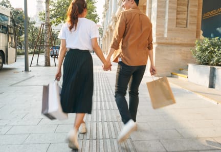 a man and woman walking down the street with shopping bags