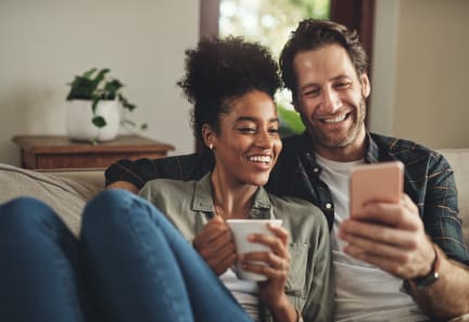a man and woman sitting on a couch looking at a cell phone