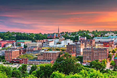 A cityscape with a church steeple stands out against a sunset sky.