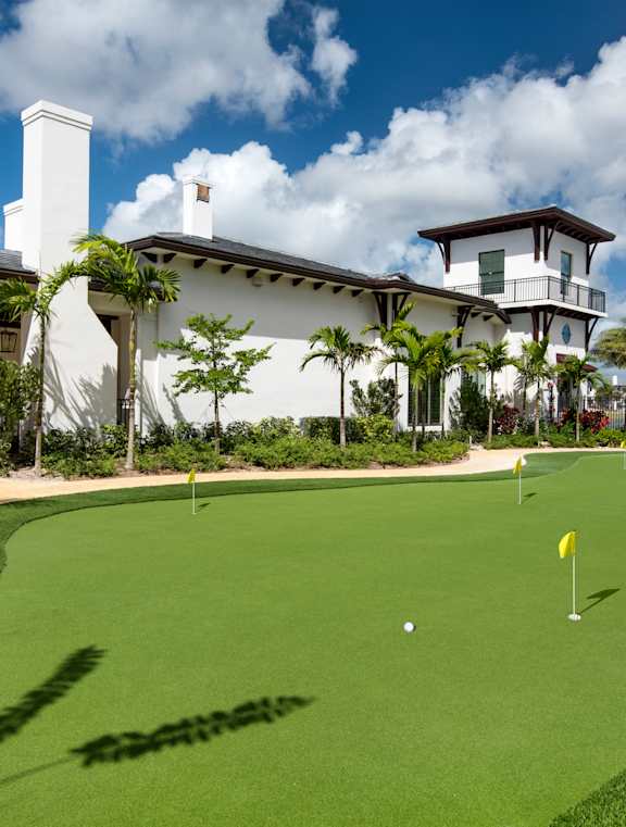 A golf course with a white building in the background.