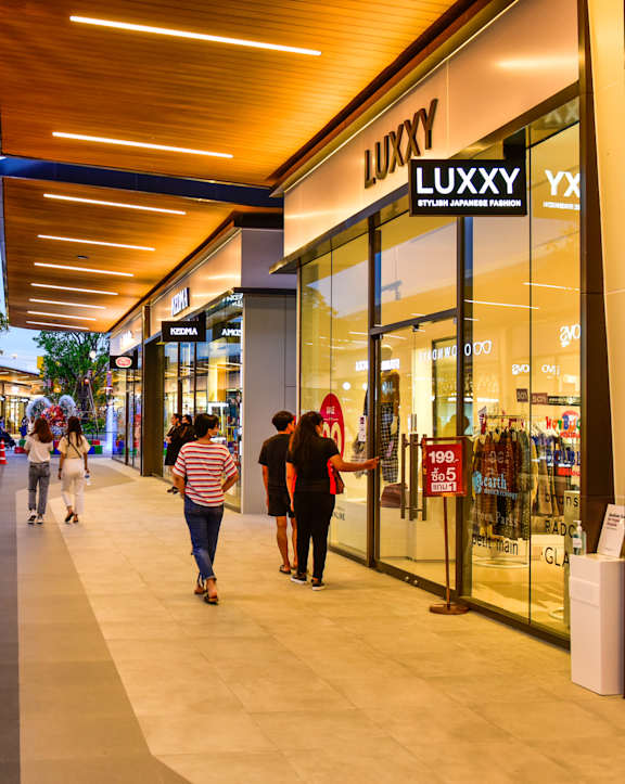 People walking in a shopping mall past a Luxury store.
